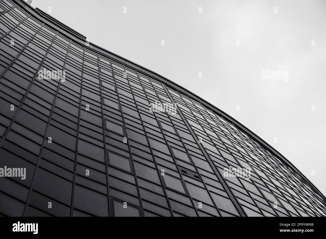 Schwarz-weißes monochromes Hochhaus mit Glasfassade, das vor der Kulisse des Himmels ragt, niedriger Winkel. Betont die hohe Höhe und das architektonische Design des Gebäudes Stockfoto