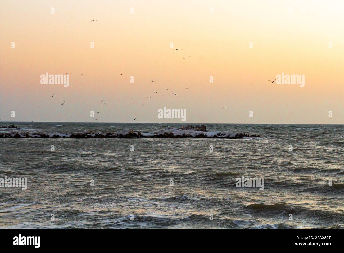 Nahaufnahme des eisigen Meeres, gefrorene Wellen, Felsen und Sonnenblendung auf dem Eis. Stockfoto