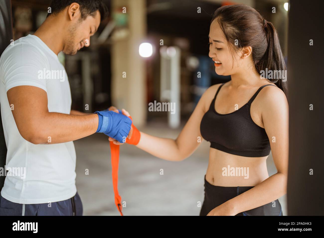 Ein Boxtrainer, der der Boxerin hilft, die Boxhandschuhe zu tragen Stockfoto