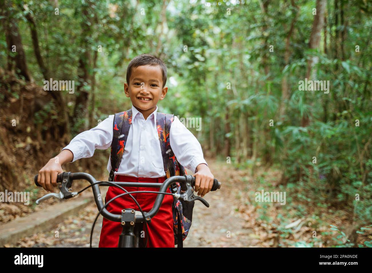 Ein männlicher Grundschüler, der Fahrrad fährt und lächelt Stockfoto