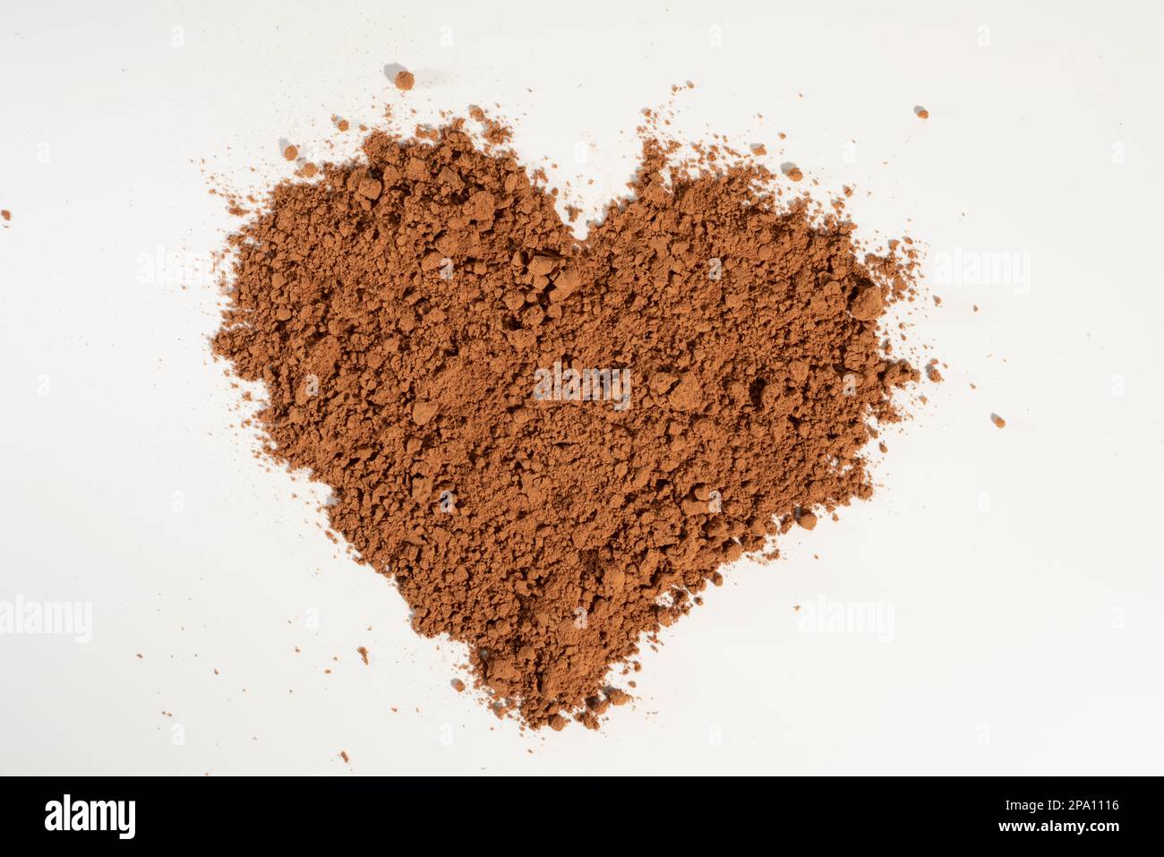Herzförmiges Kakaopulver, gehärtet auf weißem Hintergrund. Stockfoto
