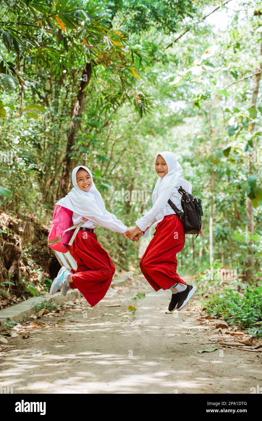 Zwei Grundschülerinnen in Uniform springen glücklich Stockfoto
