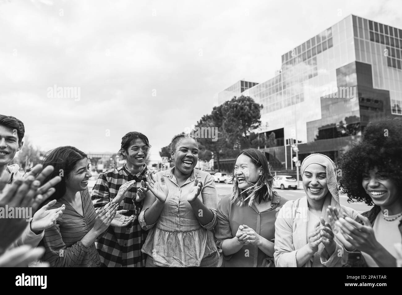 Junge, vielfältige Menschen feiern gemeinsam im Freien – Fokus auf afrikanisches kurvenreiches Mädchengesicht – Schwarz-Weiß-Bearbeitung Stockfoto