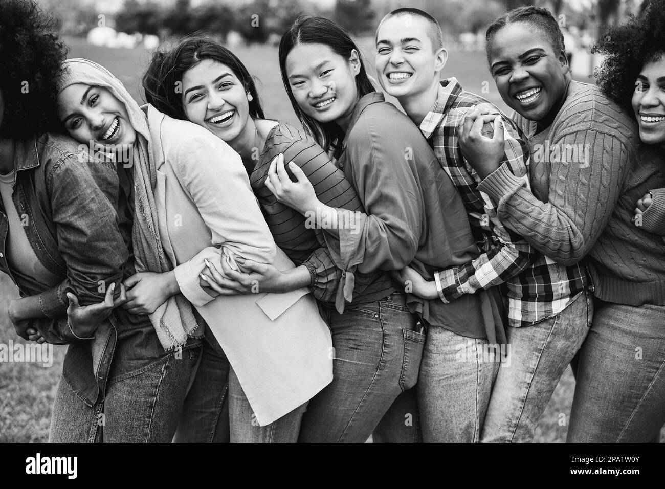 Junge, multiethnische Frauen, die Spaß miteinander haben, draußen zu lachen - Fokus auf afrikanisches Mädchengesicht - Schwarz-Weiß-Schnitt Stockfoto