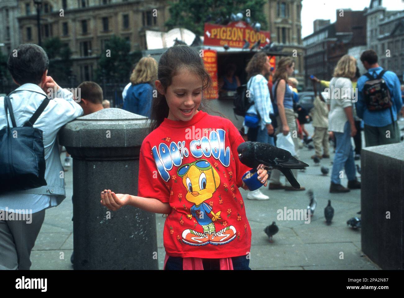 Das junge Mädchen hat Spaß beim Füttern einer Taube am Trafalgar Square im Zentrum von London. Stockfoto