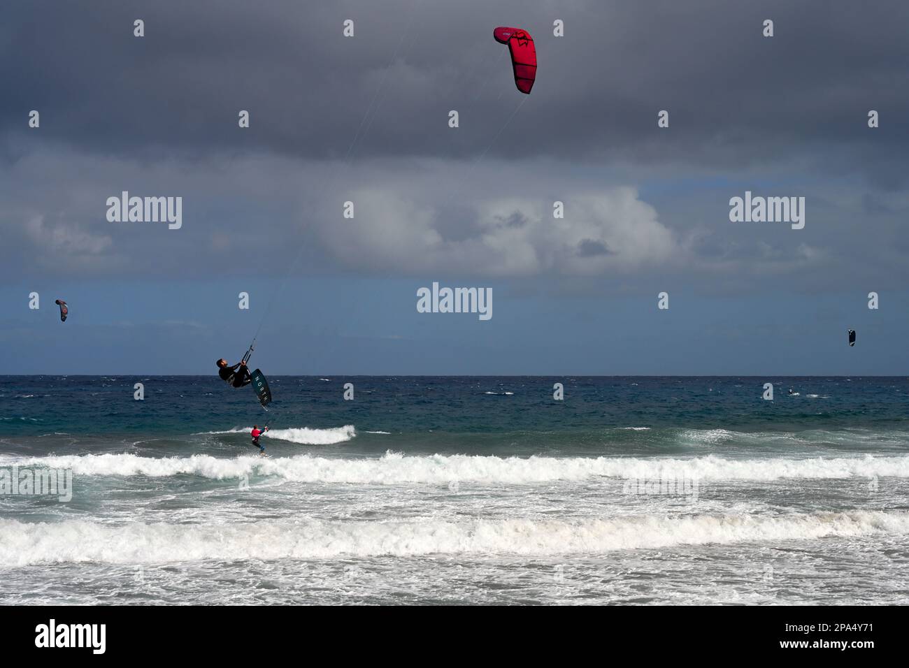 Kitesurfer auf See, die mit großen Surfen in die Luft fliegen, Playa de Vargas, Las Palmas, Spanien Stockfoto