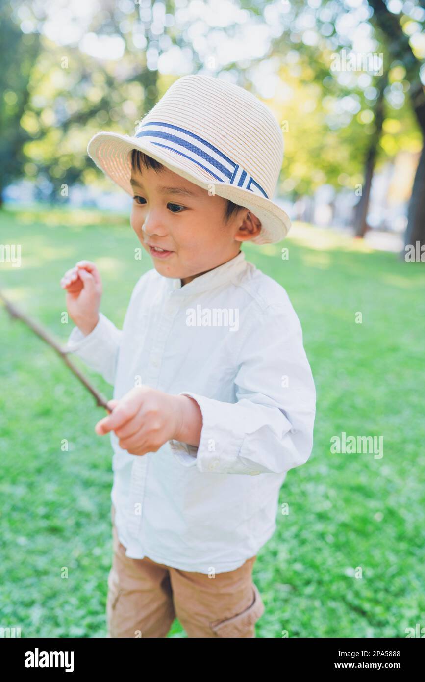 Kinderporträt - Ein kleiner Junge spielt in einem Garten. Stockfoto