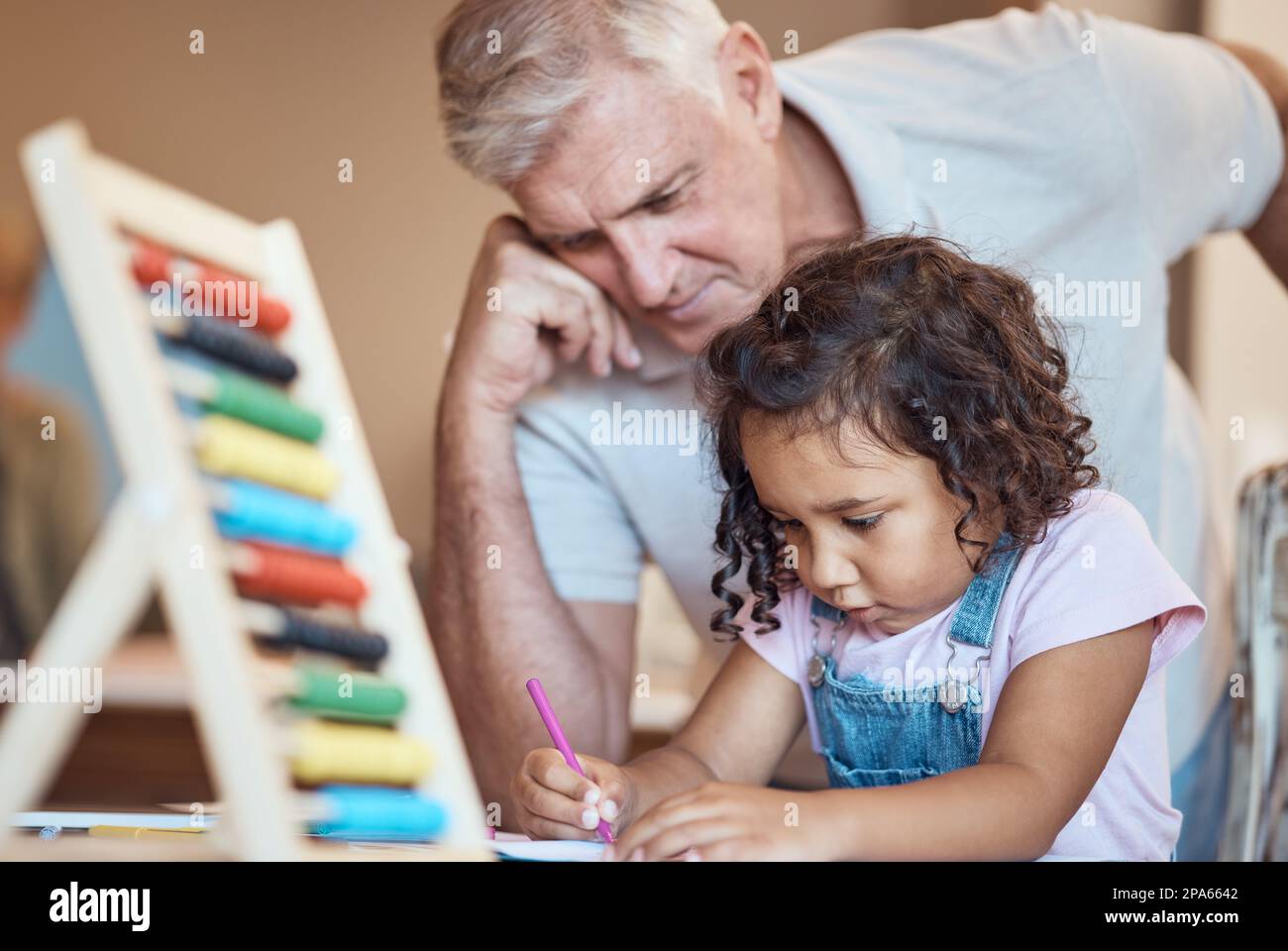 Kind, Lernen und Vater lehren mit Abacus gemeinsam für die Entwicklung. Älterer Mann, Großelternteil oder Lehrer mit einem jungen Mädchen, das im Buch schreibt Stockfoto