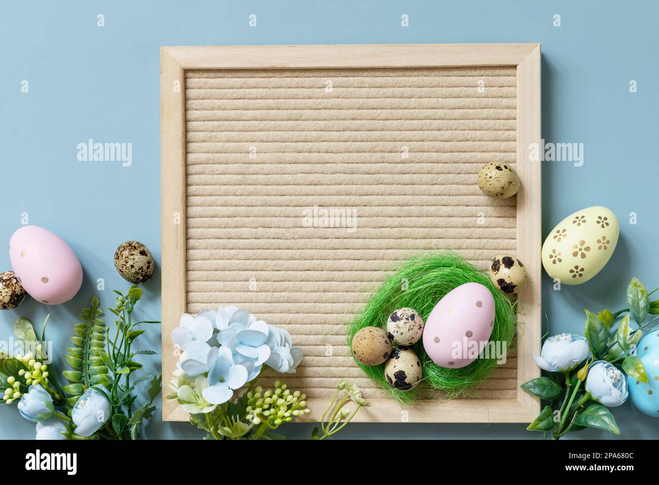 Brieftafel, Ostereier und Frühlingsblumen auf pastellblauem Hintergrund. Frühlingskonzept zur Begrüßung. Stockfoto