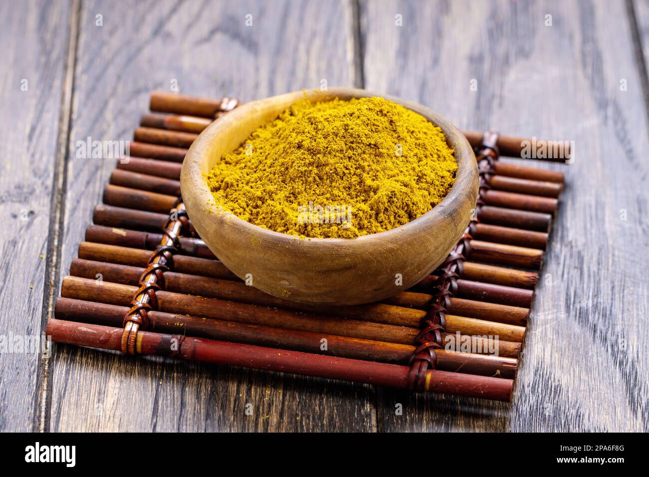 Currypulver wird in einer Holzschüssel auf dem Tisch zubereitet Stockfoto