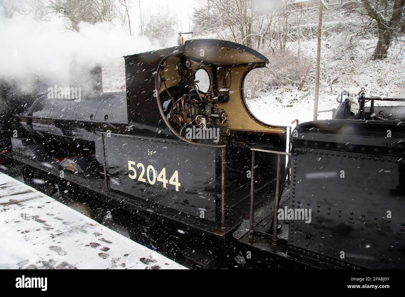 Die Dampflokomotive 52044 Klasse 25 Ironclad aus dem Film Railway Children erwartet Sie im Schnee vor der Abfahrt am Bahnhof Oxenhope Stockfoto