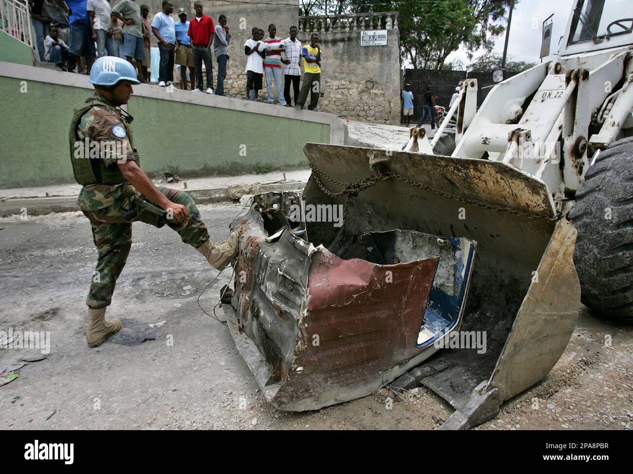 A UN peacekeeper pushes debris into the shovel of a bulldozer while clearing away a makeshift roadblock in Port-au-Prince, Thursday, April 10, 2008. Protesters abandoned roadblocks and businesses reopened in Haiti's debris-littered capital but some warned chaos will quickly return if the government does not rein in soaring food prices. (AP Photo/Brennan Linsley) Stockfoto