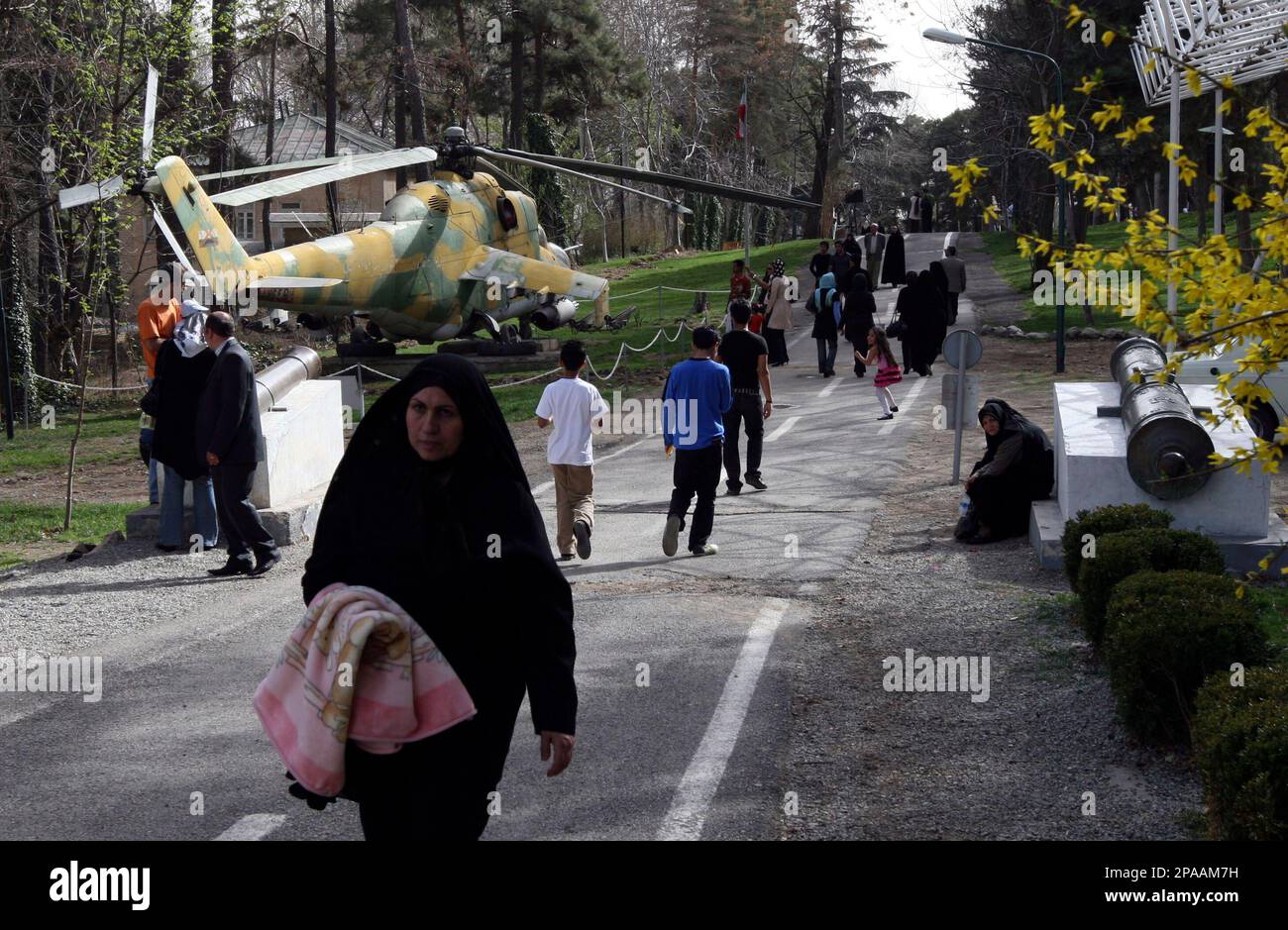 Iranians walk past an Iraqi helicopter, left, captured during the Iran-Iraq war (1980-88), on display at a military museum, part of the Sa'ad abad Cultural Complex in northern Tehran, Iran on Sunday March. 23, 2008, as they celebrate the Iranian New Year, Nowrooz. The Sa'ad abad Cultural Complex was founded by the Qajar dynasty in 1900 and was a residence of Shah Mohammad Reza Pahlavi, the last king of Iran who was toppled by the 1979 Islamic revolution. (AP Photo/Hasan Sarbakhshian) Stockfoto