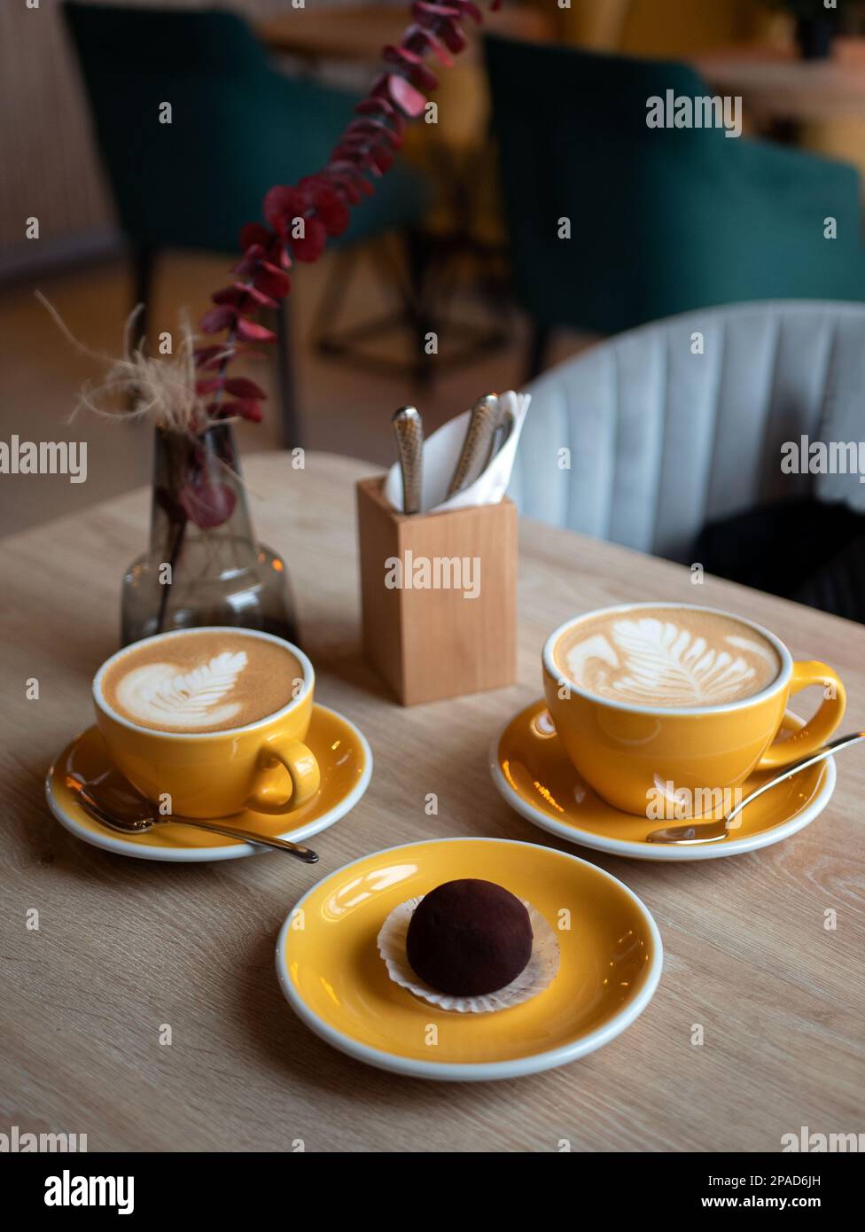 Hellgelbe Kaffeetassen mit Kaffee und Schokoladenkuchen auf dem Tisch, Nahaufnahme. Dessert im Café, selektiver Fokus Stockfoto