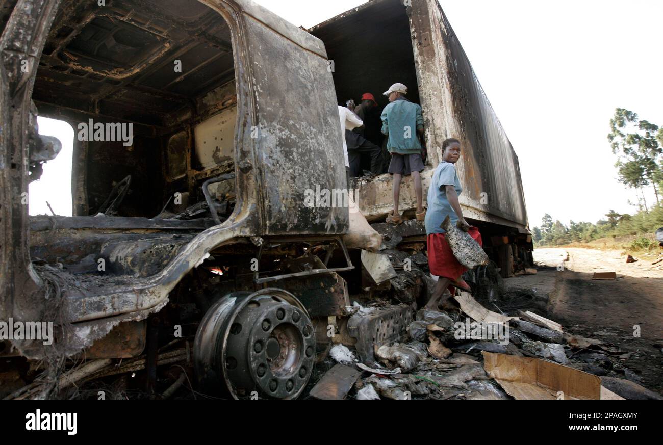 Kenyans from nearby villages remove charred fish from a truck that had ...