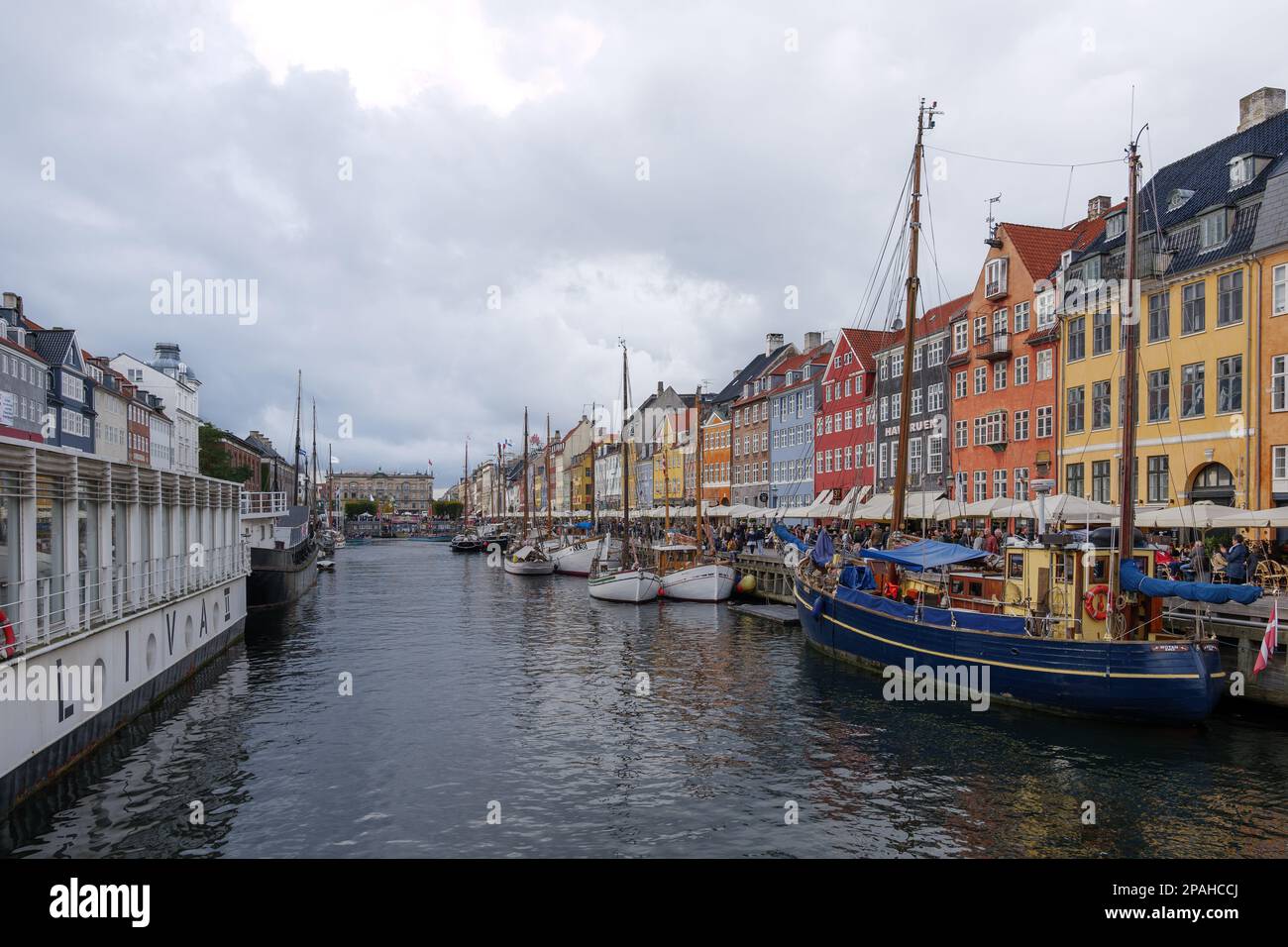 Luftaufnahme des Nyhavn-Kanals mit schwimmendem Tourboot, das voller Touristen ist, und Hintergrund der farbenfrohen berühmten Stadthäuser entlang der Uferpromenade während der Wolke Stockfoto