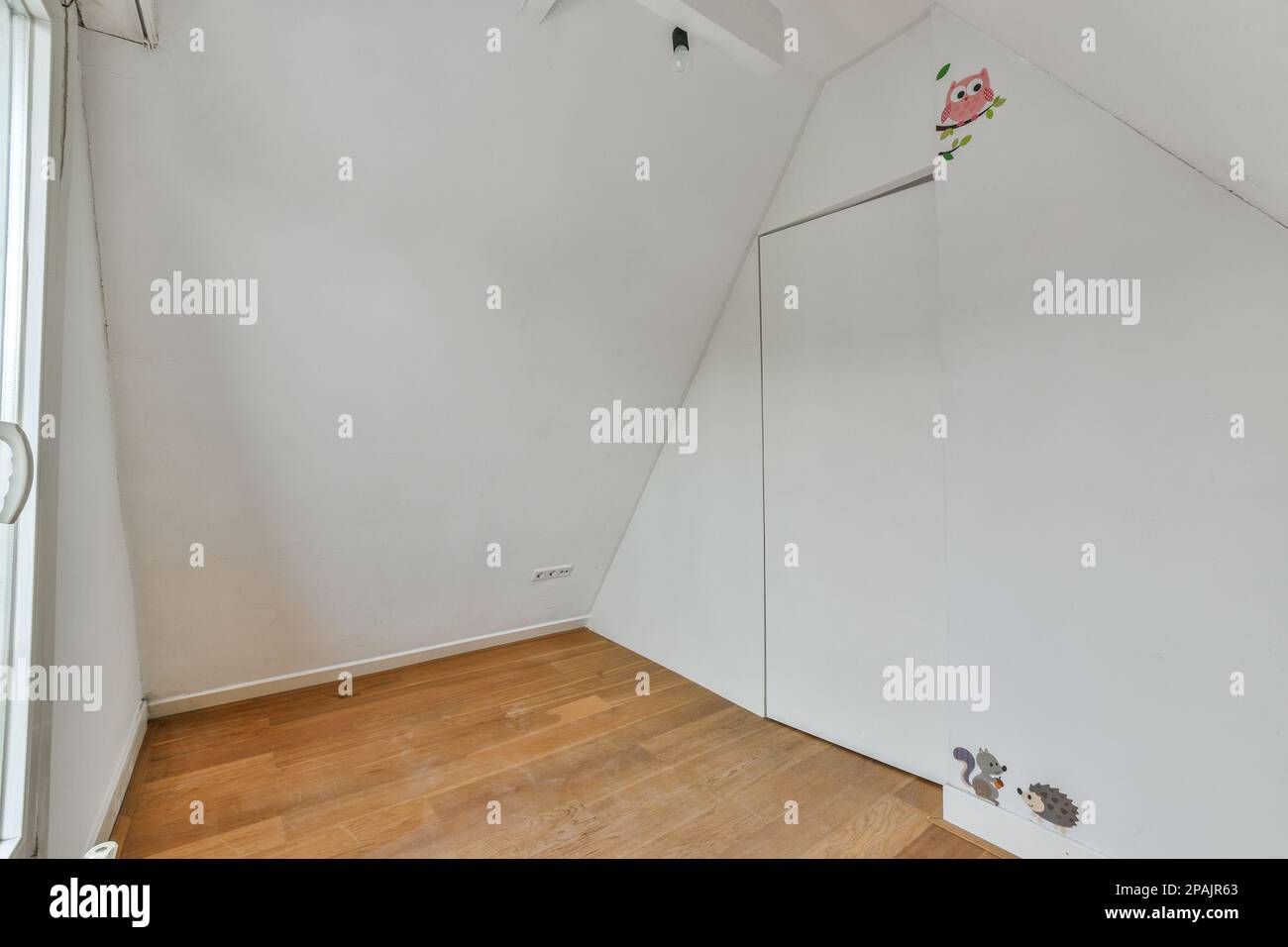Ein Zimmer mit weißen Wänden und Holzfußboden in der Ecke, es gibt einen Spiegel an der Wand neben der Tür Stockfoto
