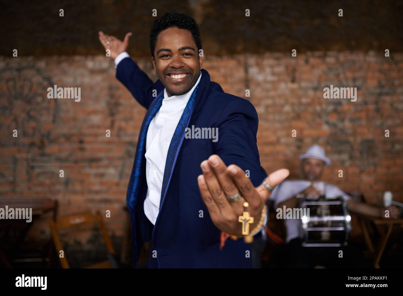 An der Religion festhalten. Porträt eines ethnischen Mannes, der auf einer Bühne steht und seine Rosenkranz-Perlen hält. Stockfoto