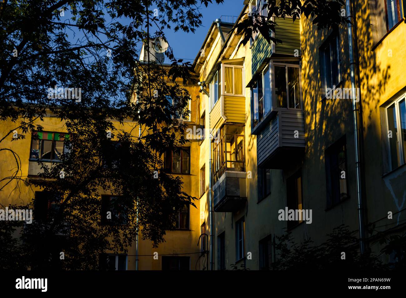 Gelbes Apartmentgebäude, das abends von der hellen Sonne beleuchtet wird Stockfoto