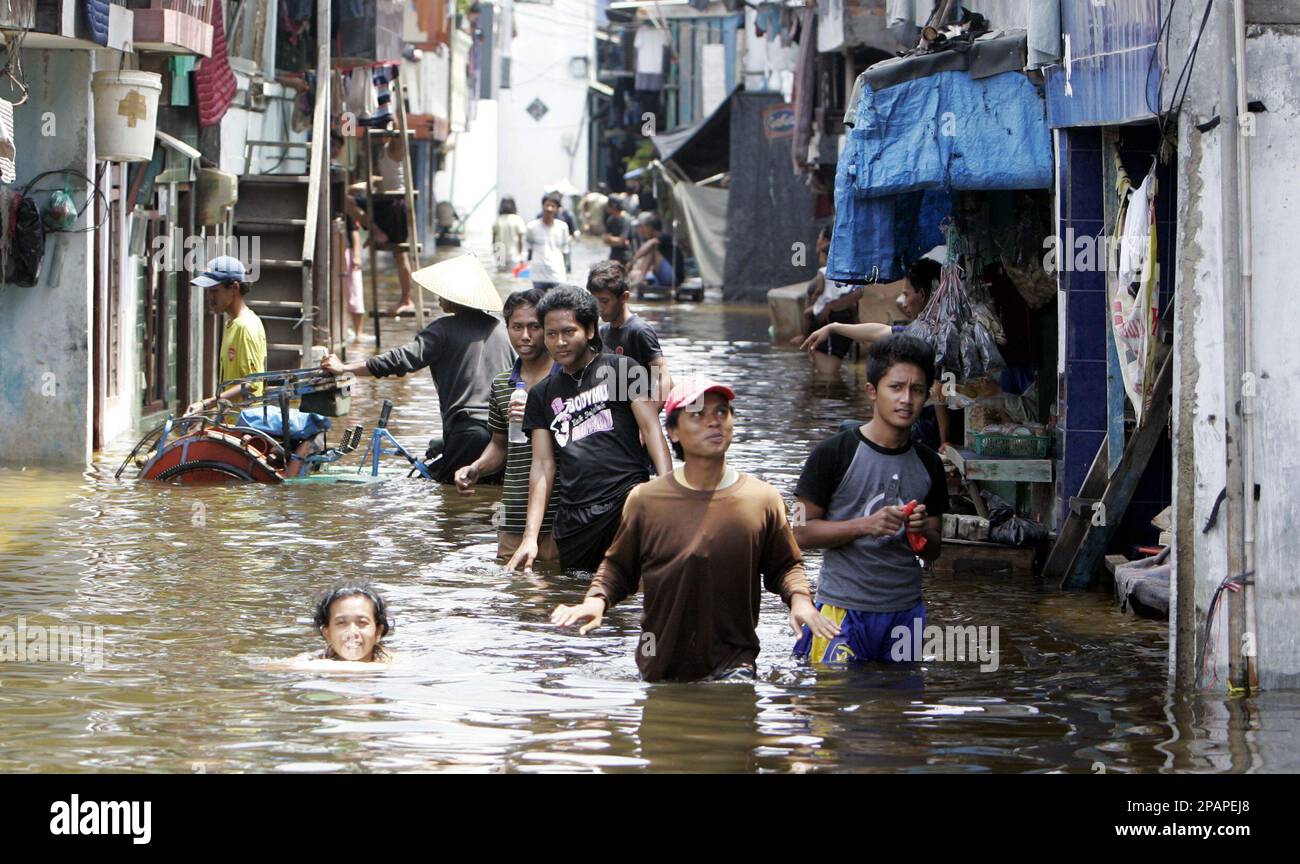 Local residents wade through a flood street in North Jakarta, Indonesia,Sunday, Dec 9, 2007. High tides flooded parts of the Indonesian capital with sea water. (AP Photo/Achmad Ibrahim) Stockfoto