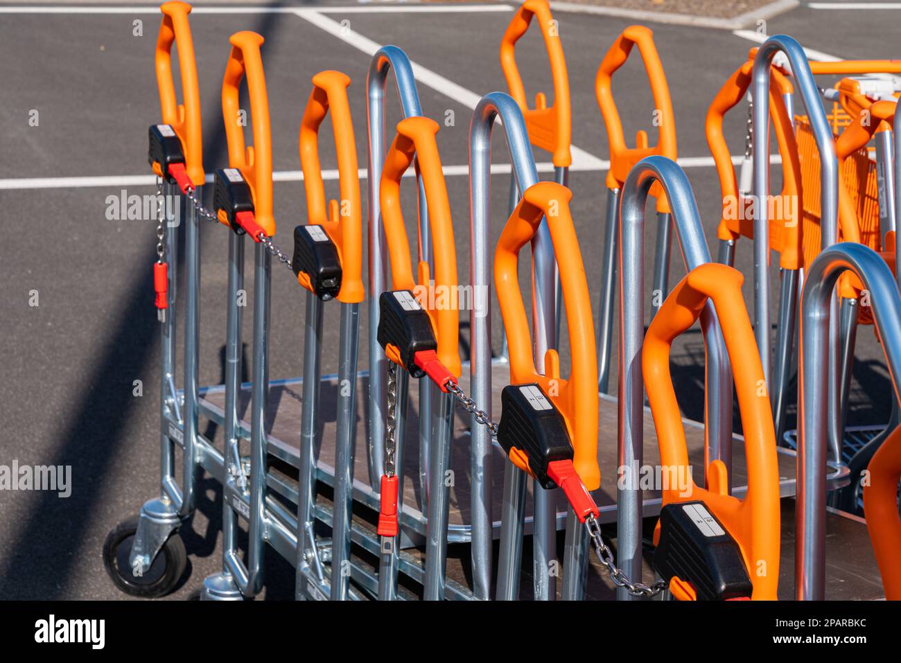 Einkaufswagen mit orangefarbenen Griffen stehen am Baumarkt. Nahaufnahme. Stockfoto