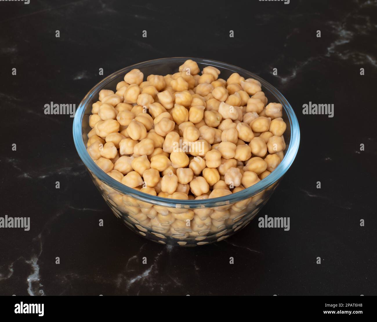 Vorgetränkte rohe Garbanzobohnen in einer Glasschüssel auf einer Küchenplatte, bereit zum Kochen Stockfoto
