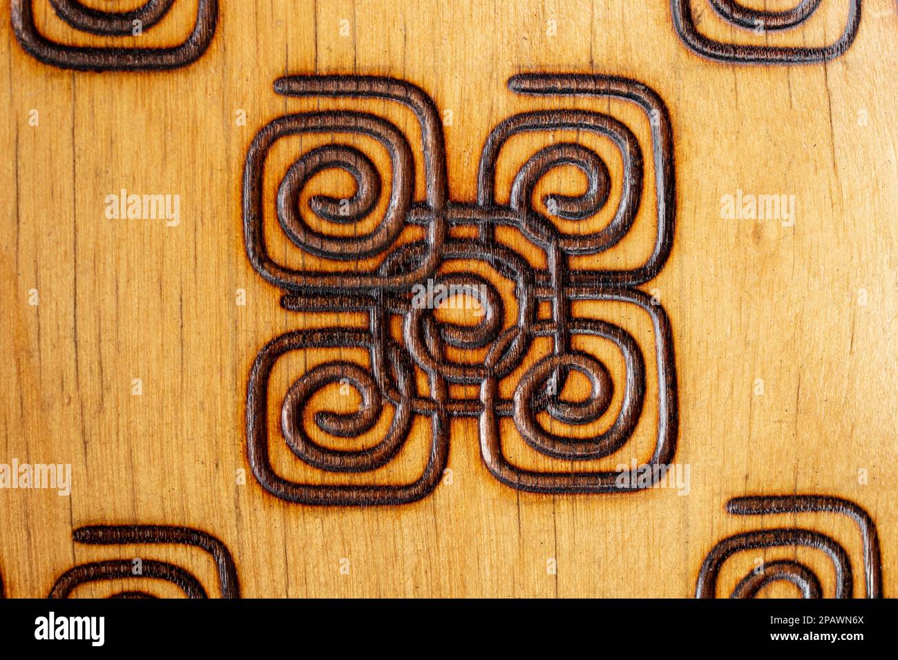 Quadratische Spiralen aus Holz mit einem Pyrografiestift, abstrakte Nahaufnahme Stockfoto