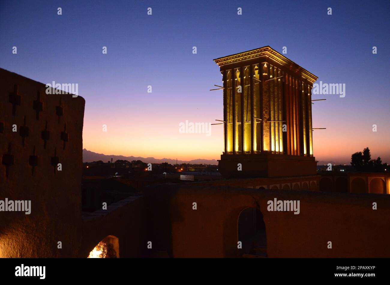 Beleuchteter Windturm in Yazd im Abendlicht mit Sonnenuntergang im Hintergrund Stockfoto
