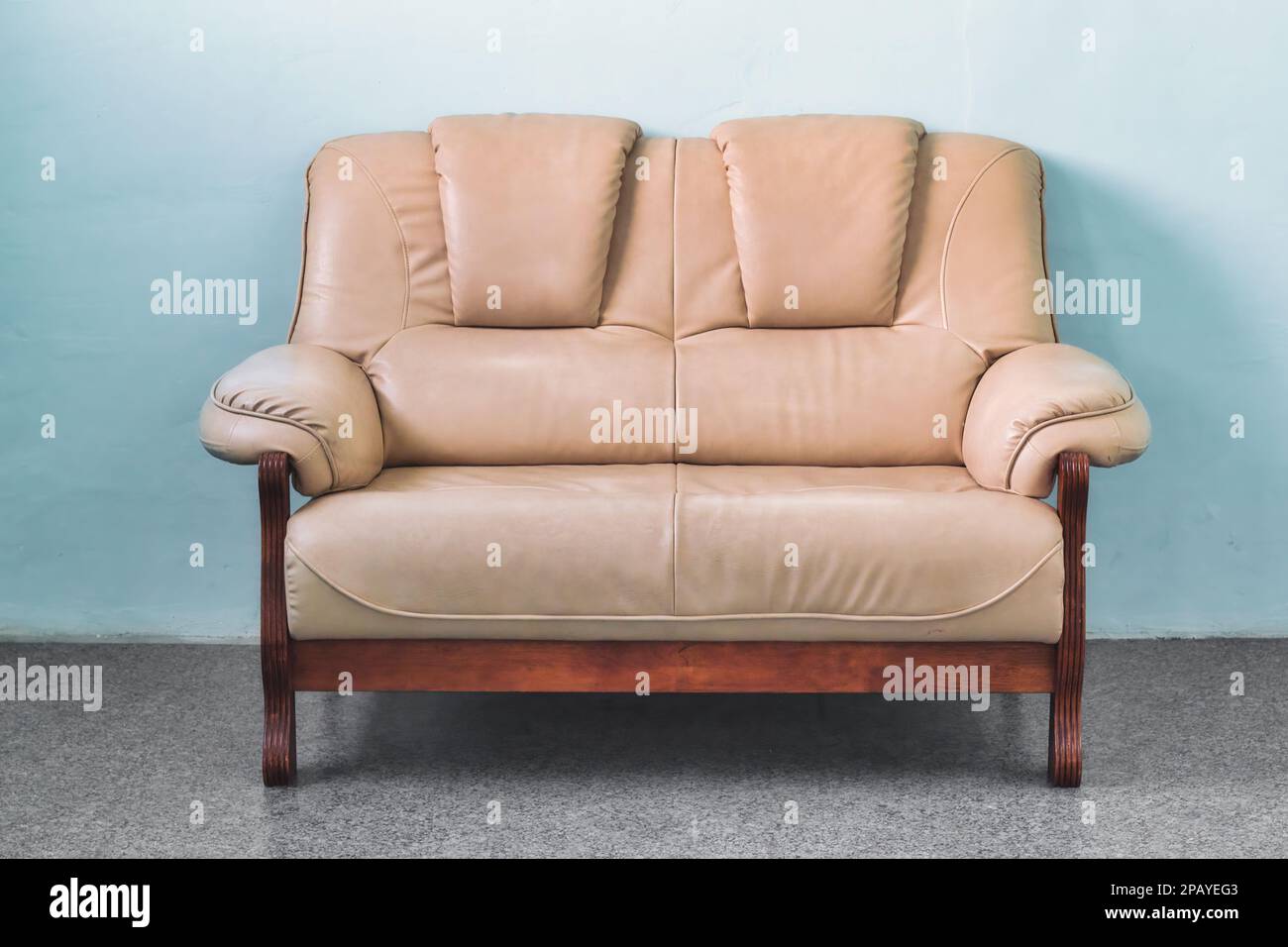 1950er beiges Ledersofa mit 2 Sitzen in einem einfachen Wohnzimmer in einem gemütlichen Apartment Stockfoto