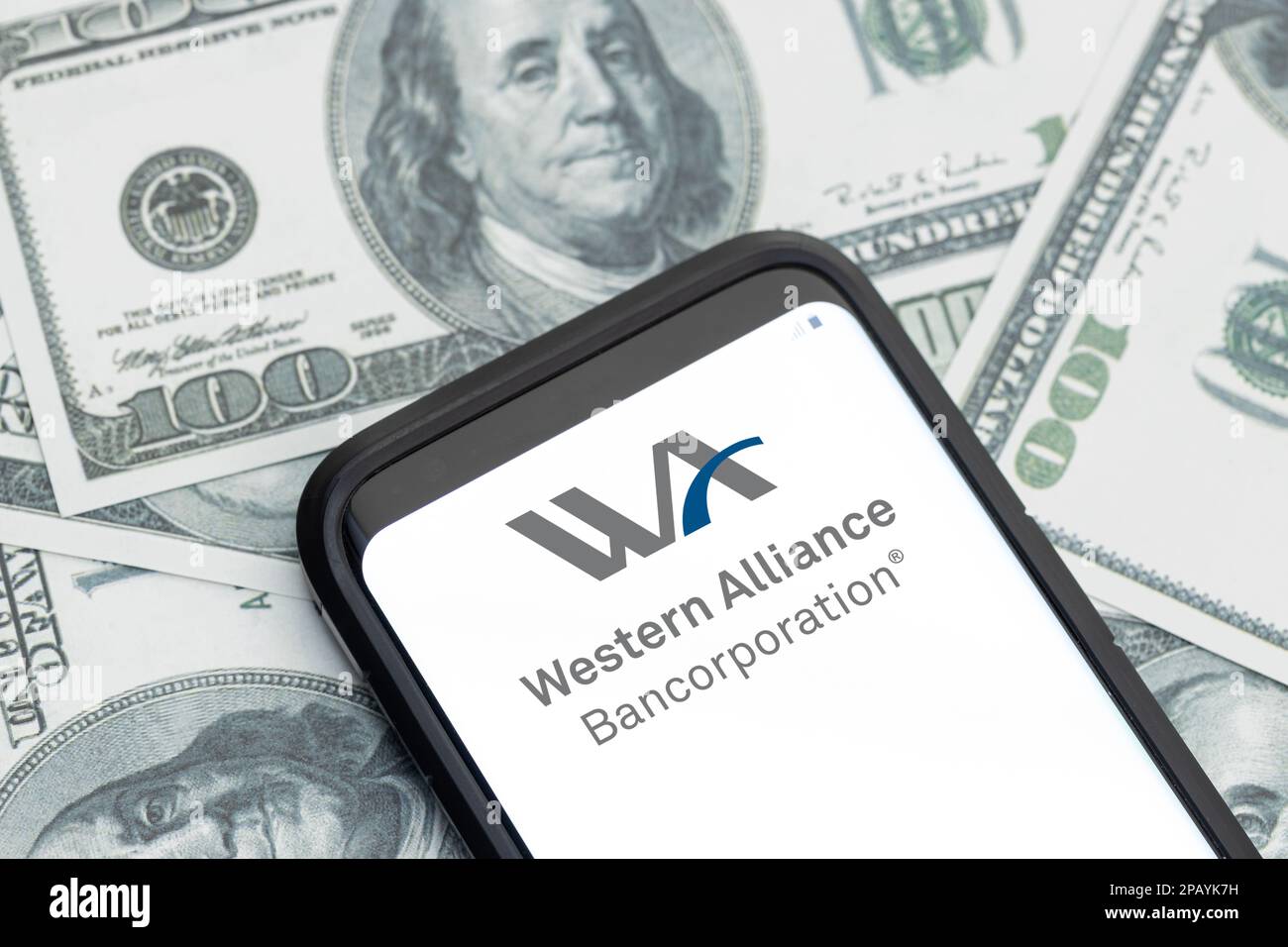 Galicien, Spanien; 12. märz 2023: Logo des Finanzdienstleisters der Western Alliance auf dem Smartphone-Bildschirm und Hintergrund der Dollarscheine Stockfoto
