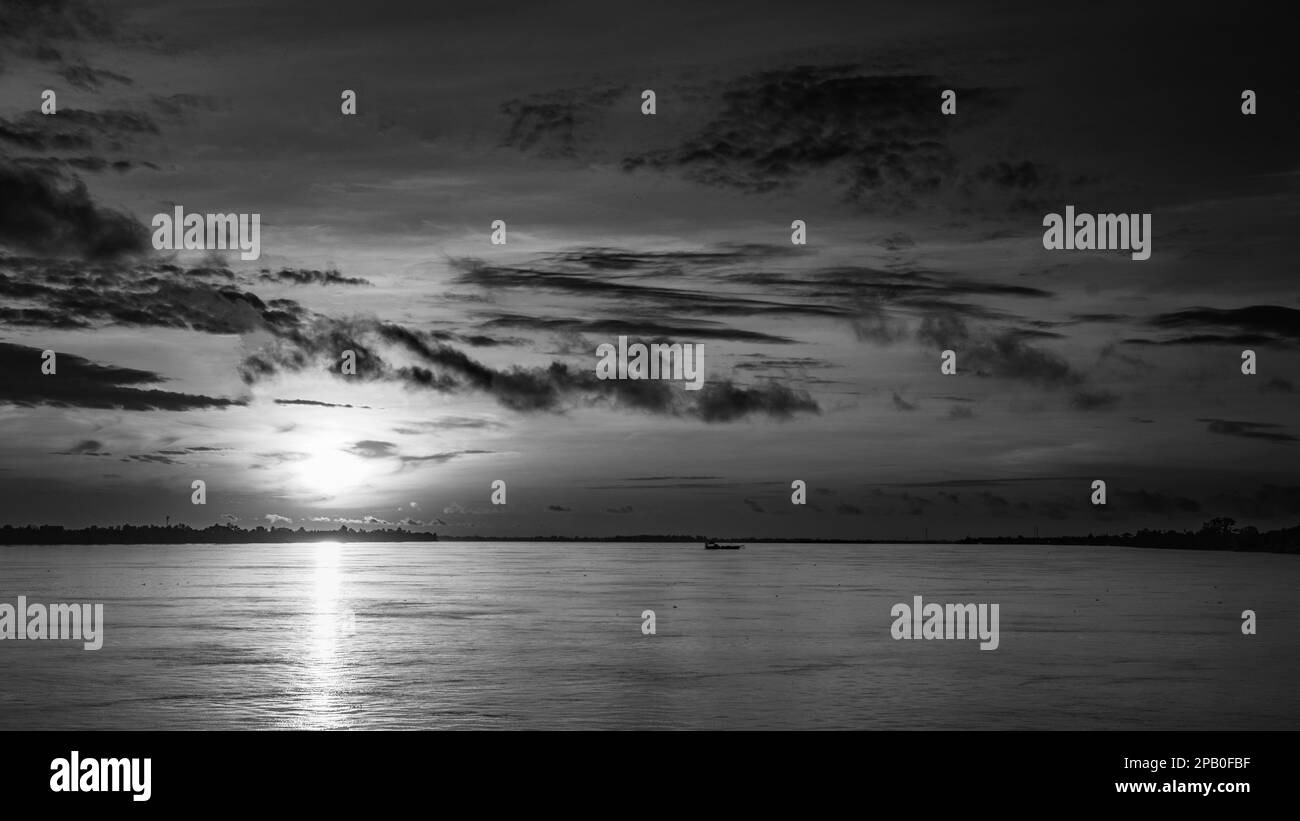 Eine kleine Fähre fährt bei Sonnenaufgang direkt stromabwärts von Phnom Penh in Kambodscha über den Mekong. Stockfoto