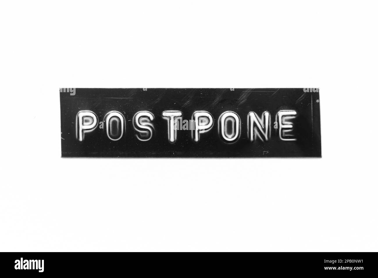 Schwarzes Banner mit geprägtem Buchstaben und Wort „postpone“ auf weißem Papierhintergrund Stockfoto