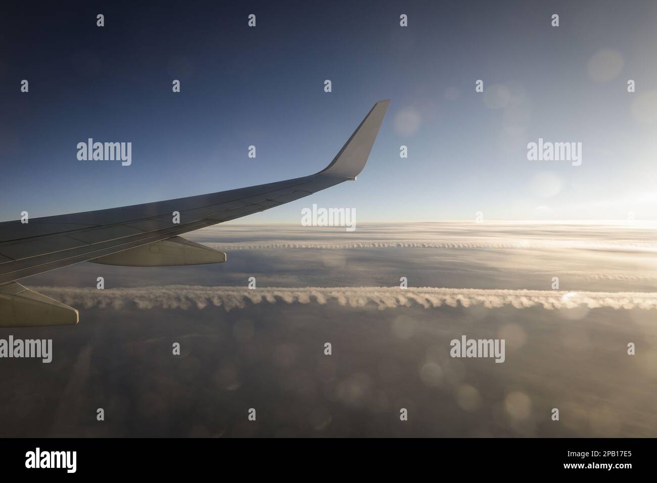 Kommerzielle Fluggesellschaften fliegen sehr früh am Morgen über den Wolken mit leichten Fackeln. Stockfoto