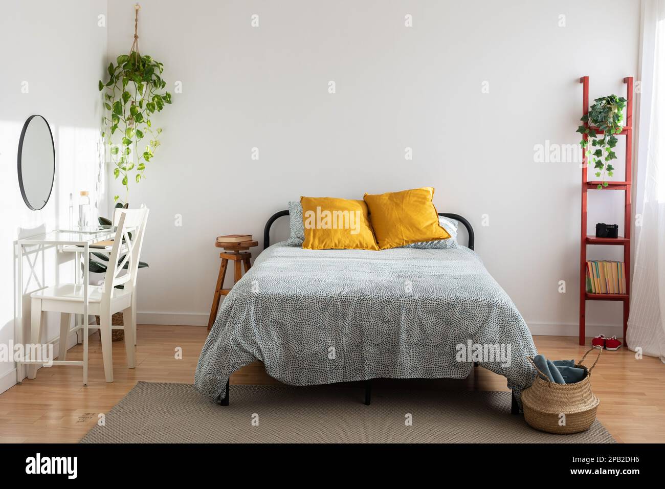 Helles, minimalistisch gemütliches Schlafzimmer mit Bett und Schreibtisch Stockfoto