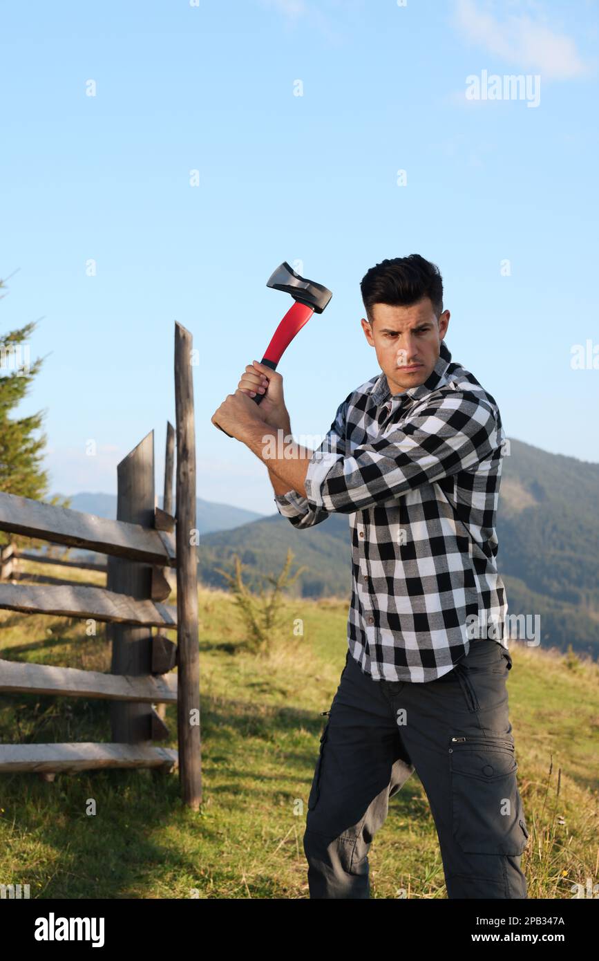 Ein hübscher Mann, der in den Bergen Axt schwingt. Professionelles Werkzeug Stockfoto Ein hübscher Mann, der in den Bergen Axt schwingt. Professionelles Werkzeug Stockfoto