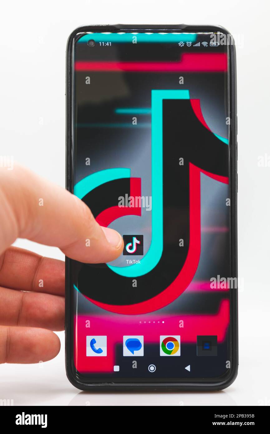 Der Finger eines Mannes zeigt auf das TikTok App-Symbol auf einem Smartphone-Bildschirm auf weißem Hintergrund Stockfoto