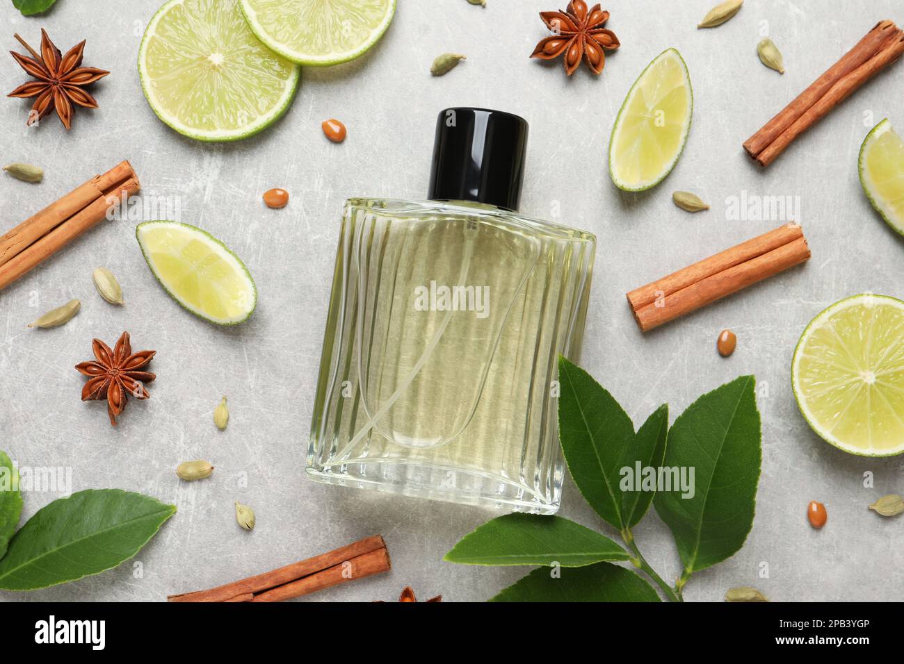 Flache Laienzusammensetzung mit einer Flasche Parfüm, Limette und Gewürzen auf hellgrauem Hintergrund Stockfoto