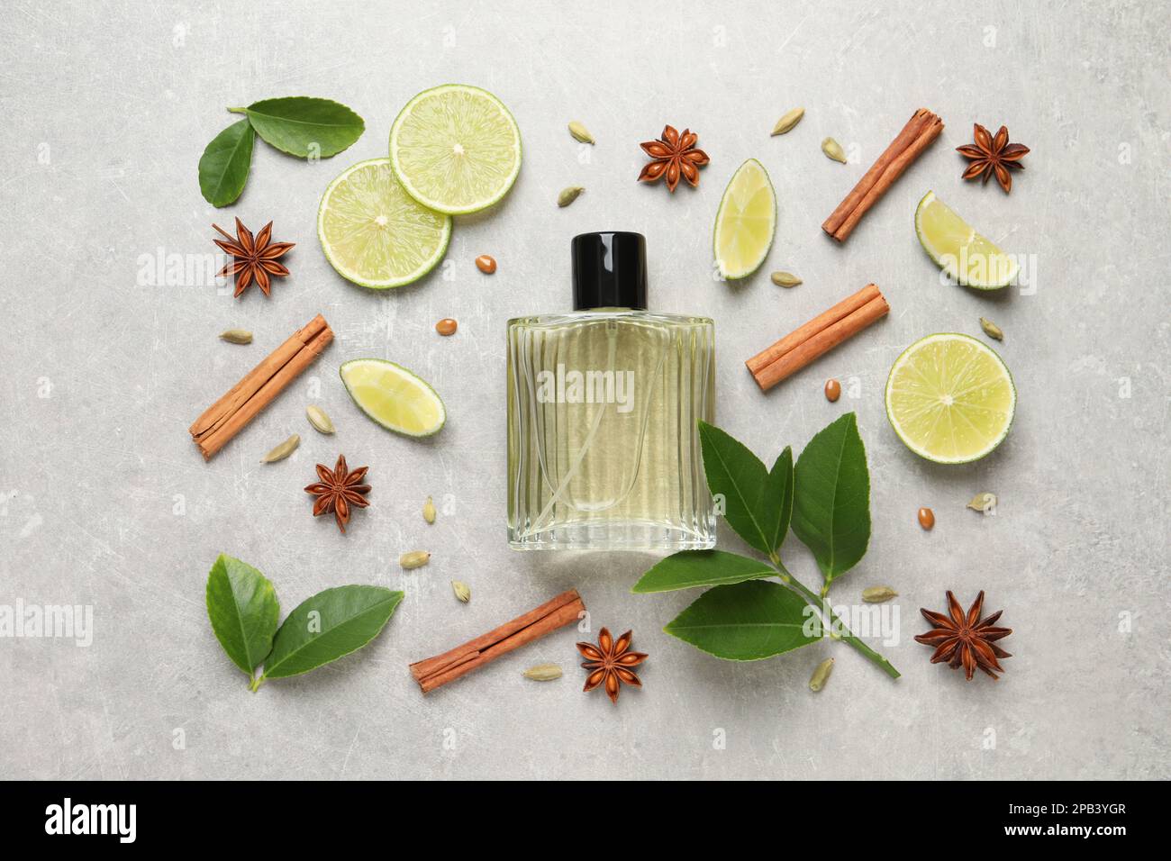 Flache Laienzusammensetzung mit einer Flasche Parfüm, Limette und Gewürzen auf hellgrauem Hintergrund Stockfoto