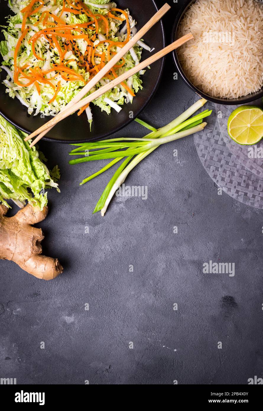 Zutaten für die Zubereitung des vietnamesischen Abendessens: Reispapier, Reis, napakohl, Ingwer, grüne Zwiebeln, Salat. Asiatische Kochzutaten. Draufsicht. Ich mache einen Wettbewerb Stockfoto