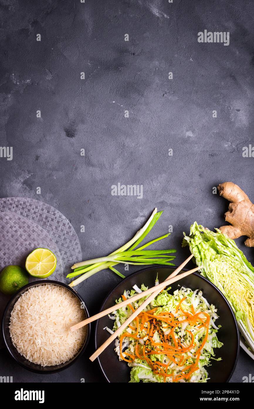 Zutaten für die Zubereitung des vietnamesischen Abendessens: Reispapier, Reis, napakohl, Ingwer, grüne Zwiebeln, Salat. Asiatische Kochzutaten. Draufsicht. Ich mache einen Wettbewerb Stockfoto