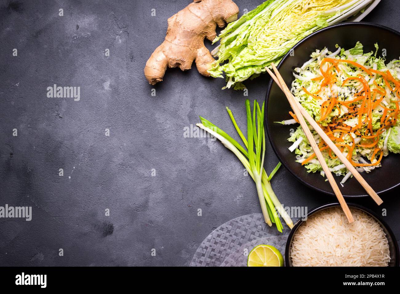 Zutaten für die Zubereitung des vietnamesischen Abendessens: Reispapier, Reis, napakohl, Ingwer, grüne Zwiebeln, Salat. Asiatische Kochzutaten. Draufsicht. Ich mache einen Wettbewerb Stockfoto