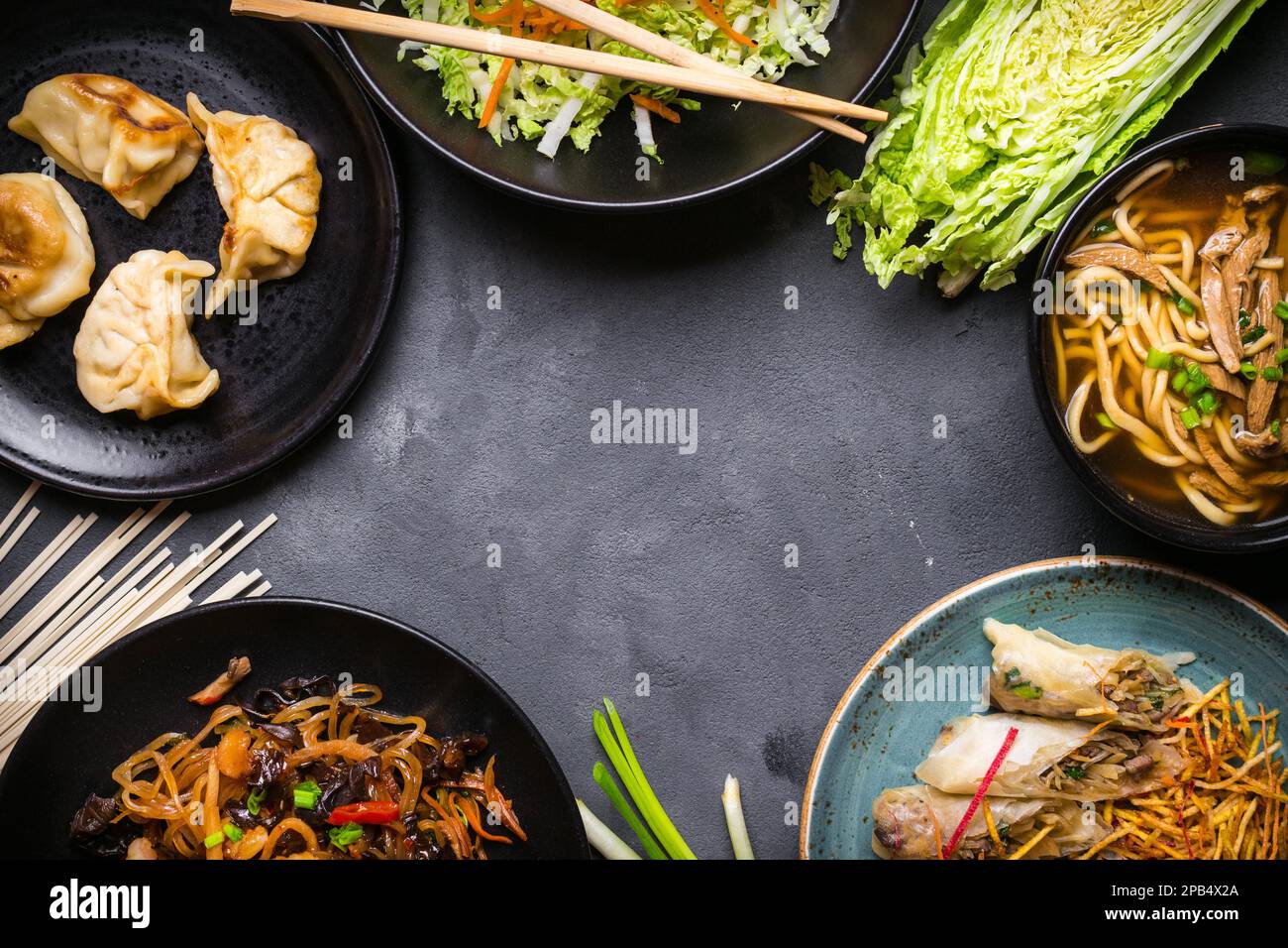 Chinesisches Essen mit dunklem Hintergrund. Chinesische Nudeln, gebratener Reis, Nudelsuppe, Dim Sum, Frühlingsrollen, Salat. Traditionelle chinesische Gerichte. Leertaste für Stockfoto
