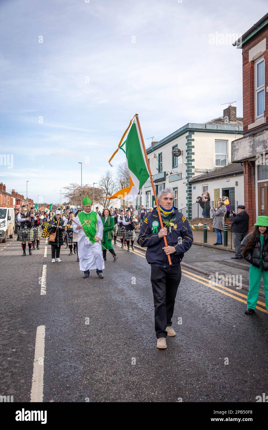 Warrington, Cheshire, Großbritannien - 12. März 2023 – Warrington Irish Club ist Gastgeber des St. Patrick's Day Parade. Beginn um 10,30 Uhr morgens vom Irish Club in der Orford Lane zum „River of Life“ in der Bridge Street im Stadtzentrum, wo ein kurzer Gottesdienst zum Gedenken an den Jahrestag des Bombenanschlags in Warrington abgehalten wurde. Die irische Flagge führte die Parade an, gefolgt von einem Mann, der als St. Patrick verkleidet war Stockfoto