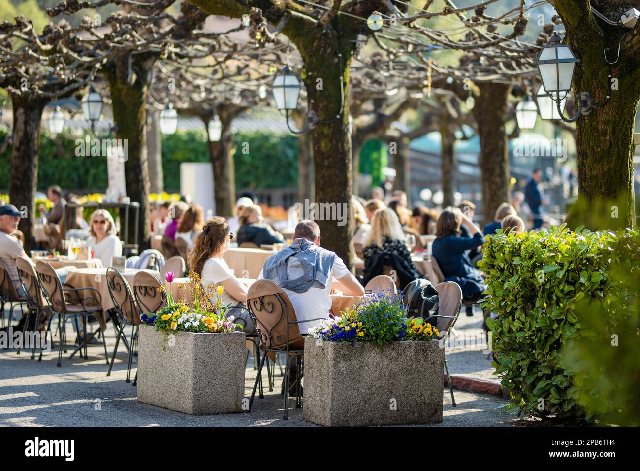 BELAGGIO, ITALIEN - APRIL 2022: Touristen und Einheimische verbringen den sonnigen Frühlingstag in Belaggio, einer Stadt am Ufer des Comer Sees. Charmante Lage mit typi Stockfoto