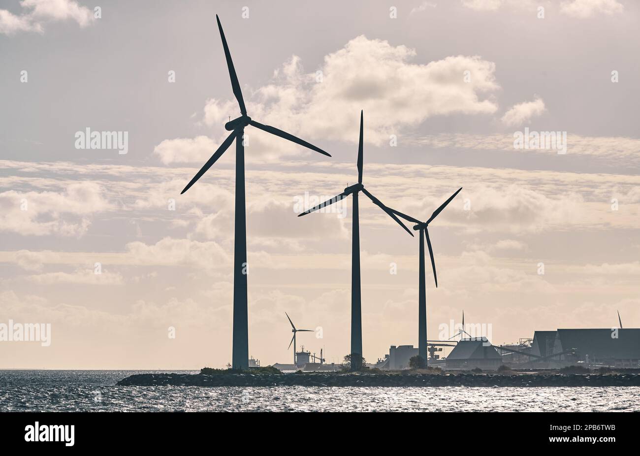 Industrielle Werft mit Silhouetten von Windturbinen bei Sonnenuntergang, Farbtönung angewendet. Stockfoto