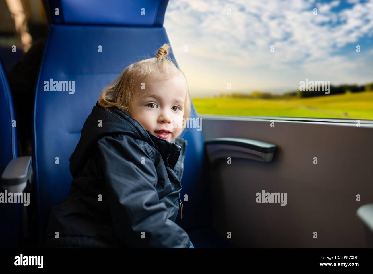 Kleiner Junge, der mit dem Zug reist. Ein kleines Kind, das im Expresszug am Fenster sitzt, während des Familienurlaubs. Kind in einem Eisenbahnwaggon. Ich fahre mit in den Urlaub Stockfoto