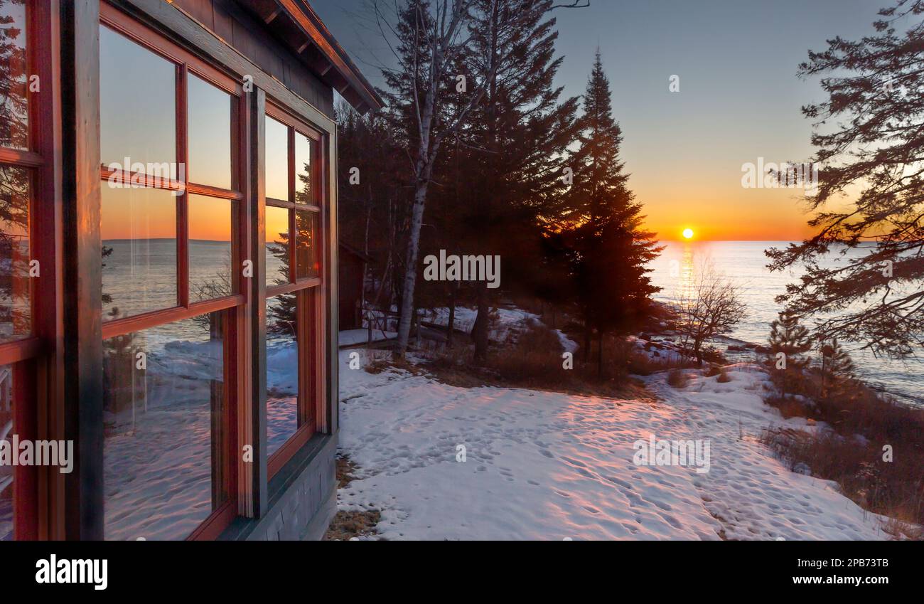 Ländliche Landschaft, Sonnenaufgang im Winter und Reflexionen in den Kabinenfenstern entlang der Nordküste des Lake Superior im Norden Minnesotas Stockfoto
