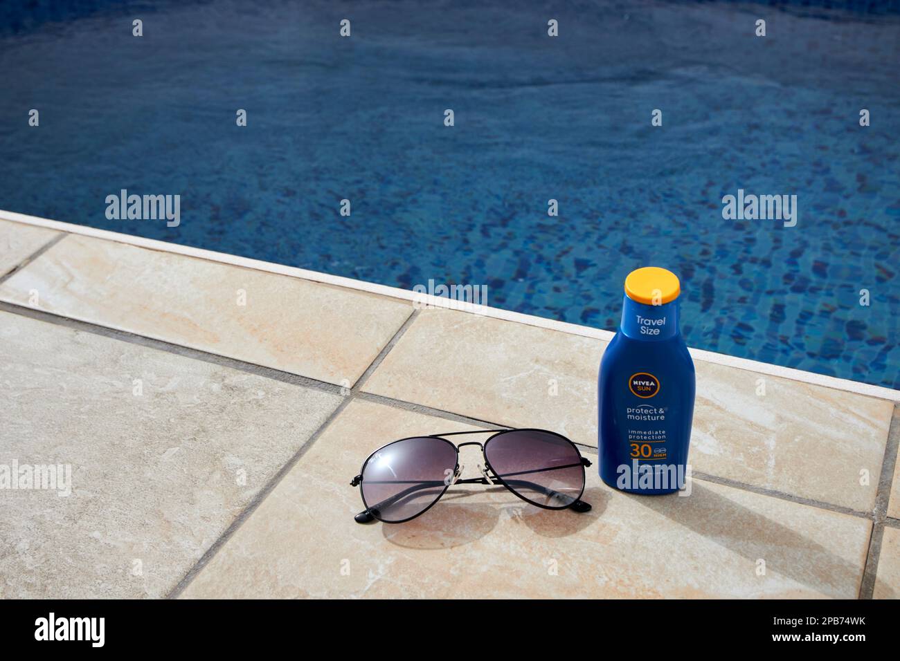Sonnencreme und Sonnenbrille auf Reisen neben einem Pool in einer Villa auf Lanzarote, Kanarische Inseln, Spanien Stockfoto