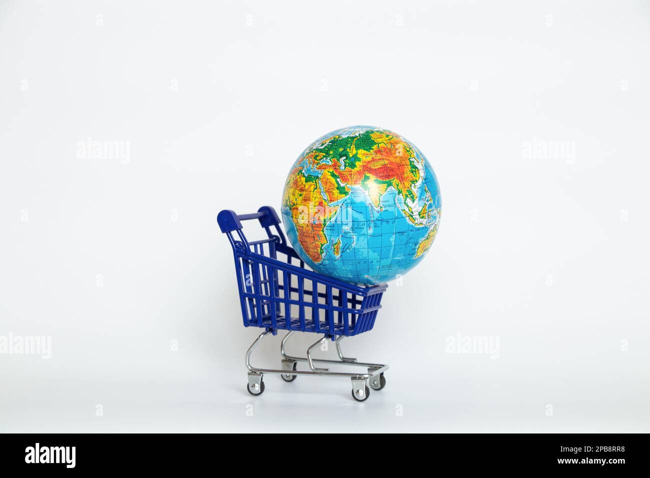 Supermarkt-Trolley und Kugel auf weißem Hintergrund Nahaufnahme, internationaler Handel Stockfoto