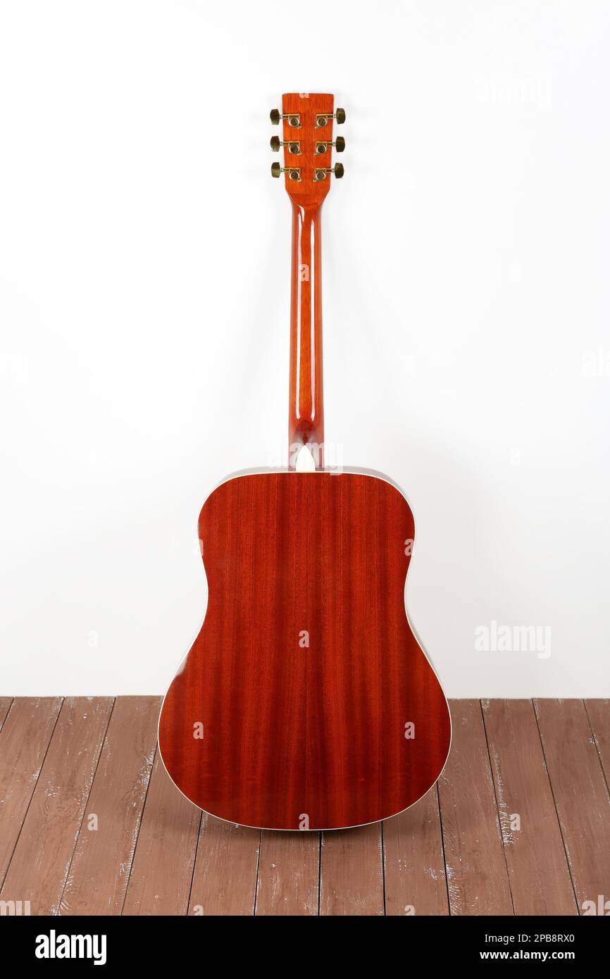 Musikinstrument - klassische Akustikgitarre mit weißem Hintergrund und Holzfußboden. Stockfoto